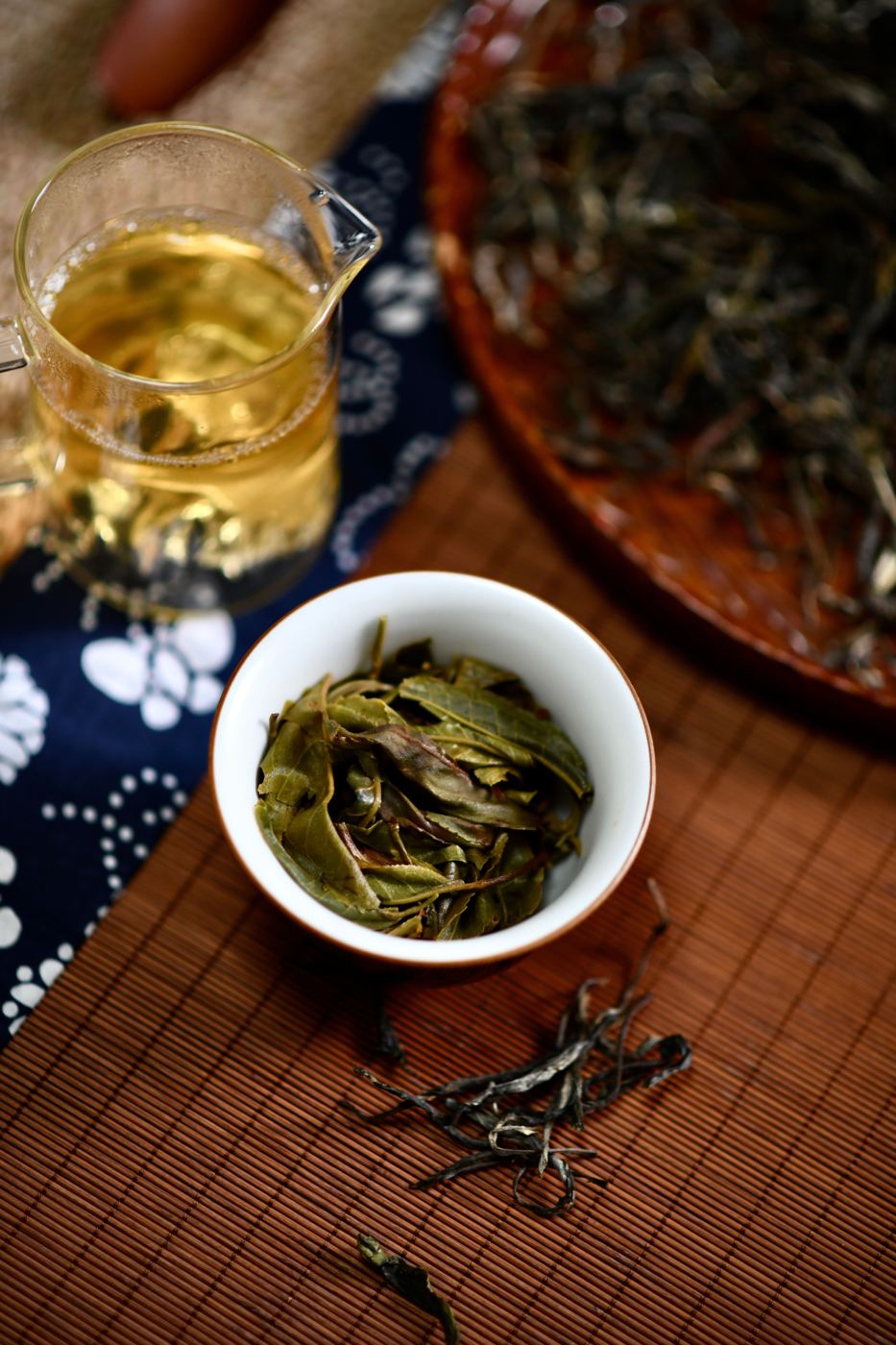 Lightly oxidized Baozhong oolong tea leaves beside a cup of pale golden brewed tea