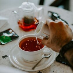 Milk being poured into a cup of black tea