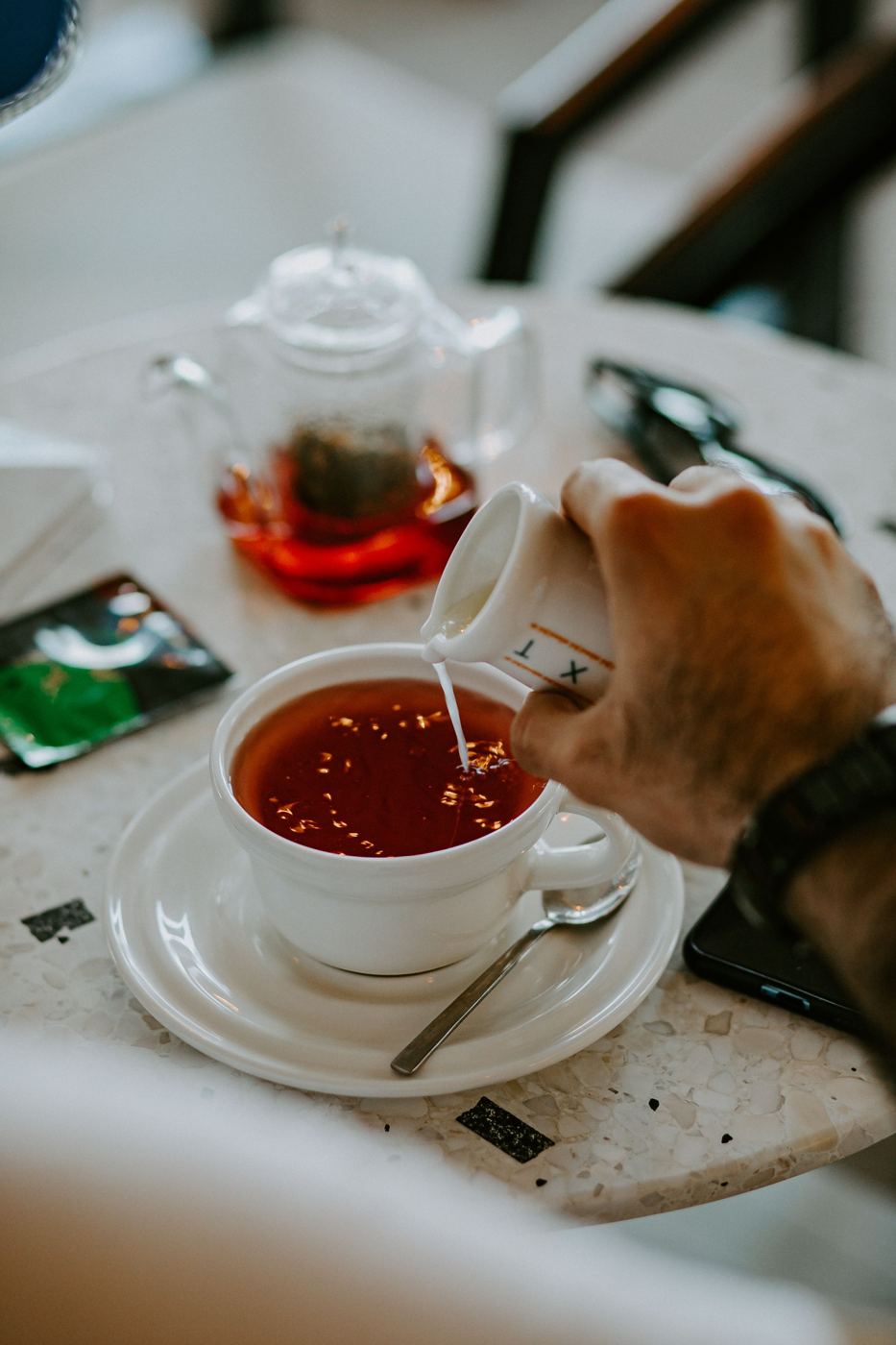 Milk being poured into a cup of black tea