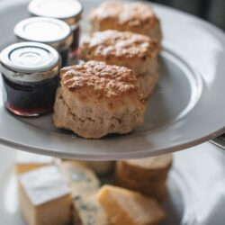 Freshly baked scones on a tiered stand next to jars of jam