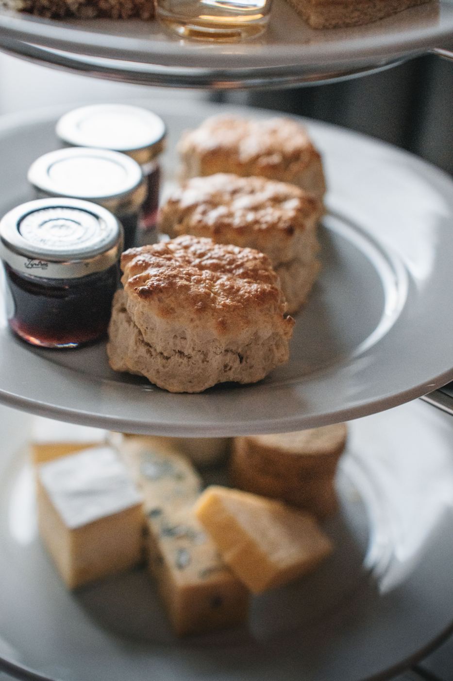 Freshly baked scones on a tiered stand next to jars of jam