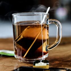 Glass mug of steaming English Breakfast black tea with tea bag steeping