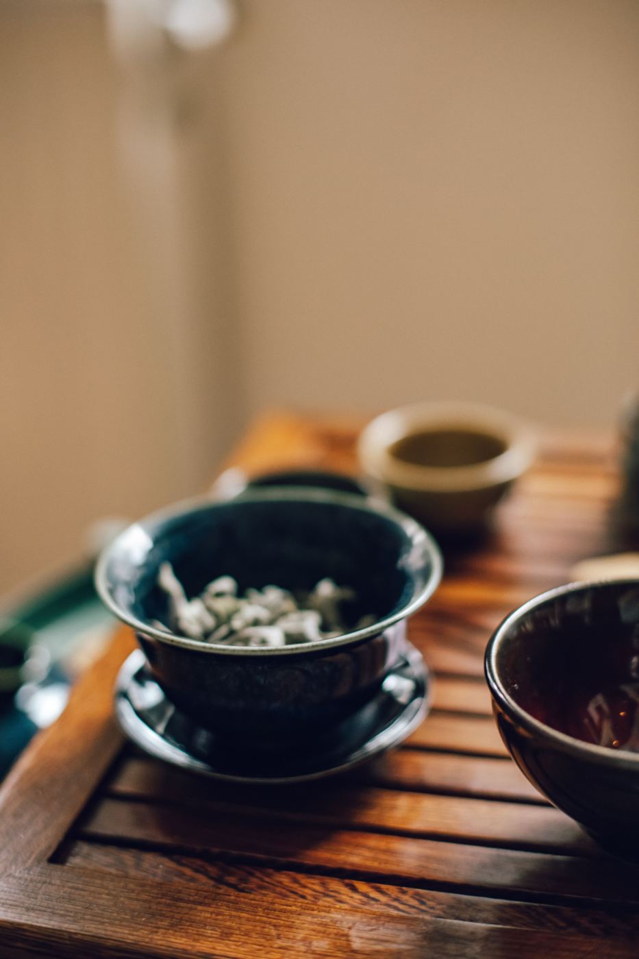 A lidded ceramic gaiwan bowl with a saucer, filled with steeped tea leaves