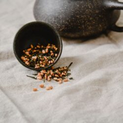 Genmaicha loose leaf tea with roasted brown rice grains beside a dark teapot