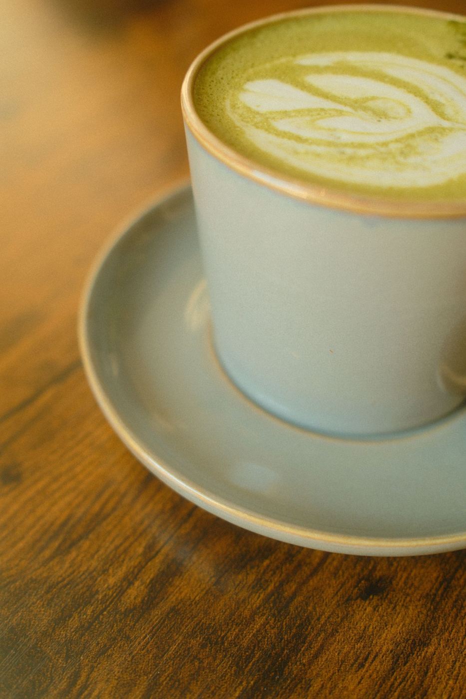 Matcha green tea latte with swirled latte art in a ceramic cup