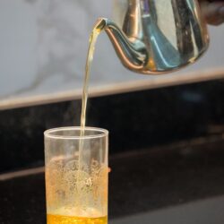 Moroccan mint tea being poured from a silver teapot into an ornate glass
