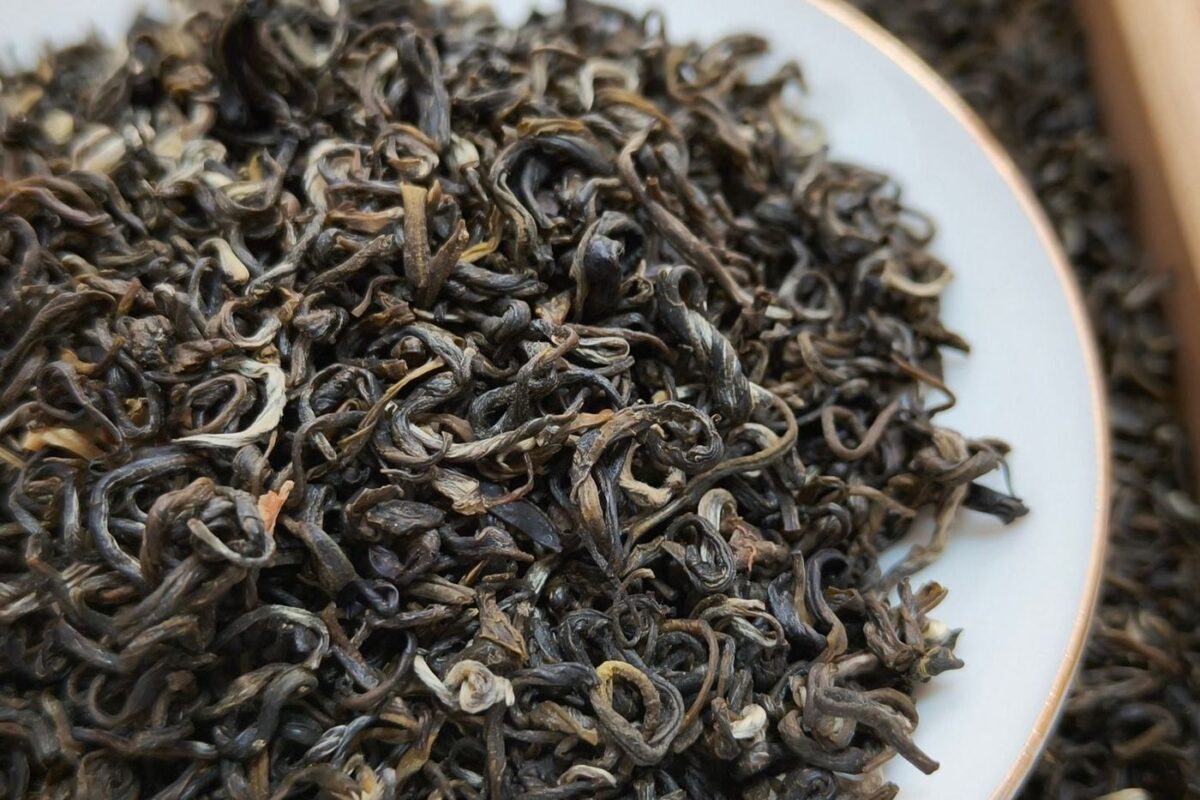 A pile of high-quality loose-leaf tea in a white tasting dish