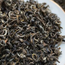 A pile of high-quality loose-leaf tea in a white tasting dish