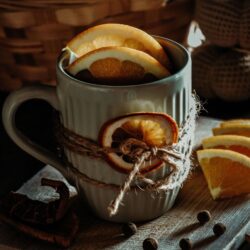 Mug of black tea garnished with dried orange slices, cinnamon sticks, and cloves