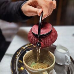 Strong Scottish Breakfast tea being poured from a teapot into a cup with a milk jug beside it