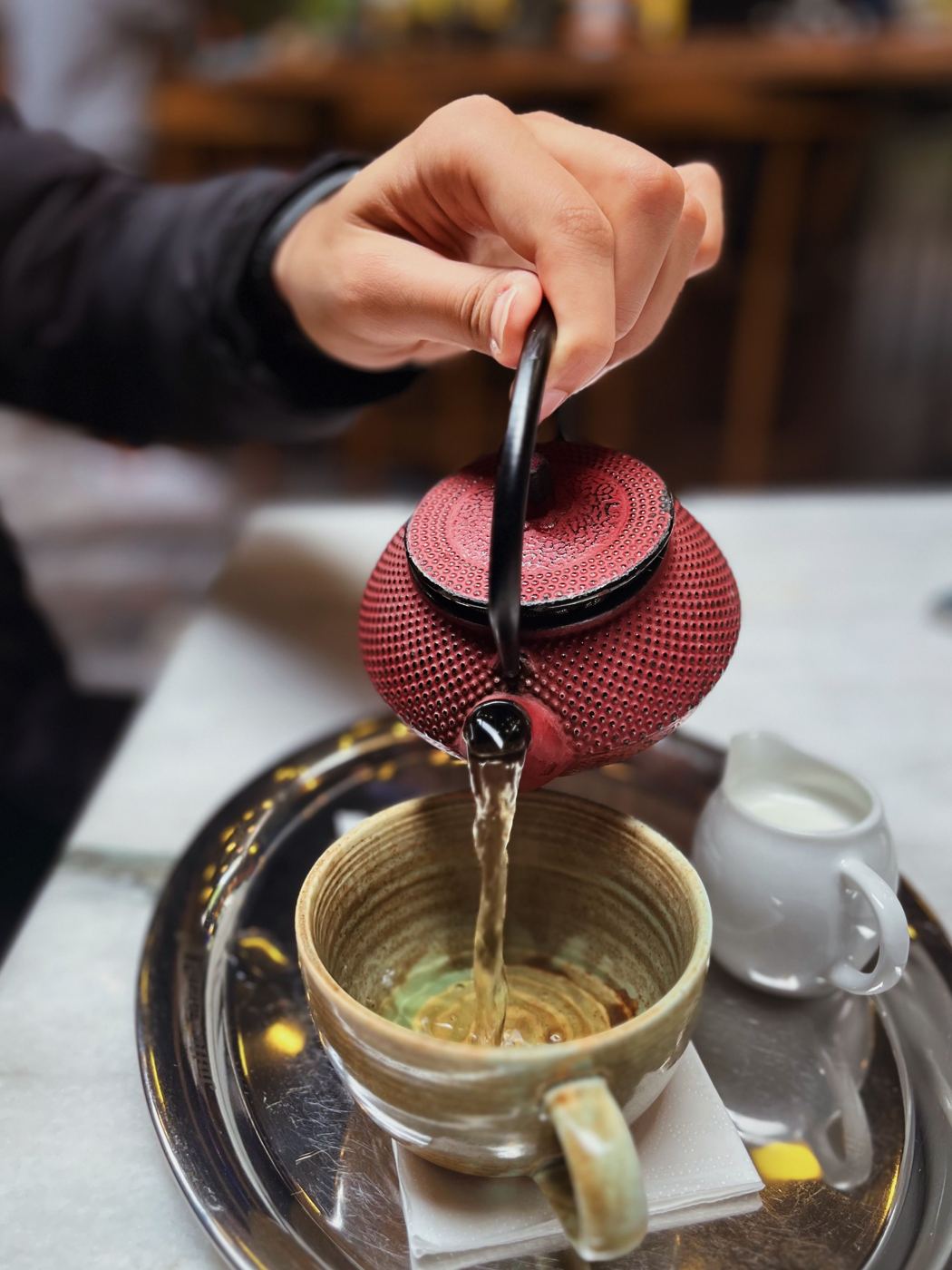 Strong Scottish Breakfast tea being poured from a teapot into a cup with a milk jug beside it