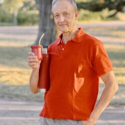 A man in a Buenos Aires park holding a traditional mate gourd with a metal bombilla straw
