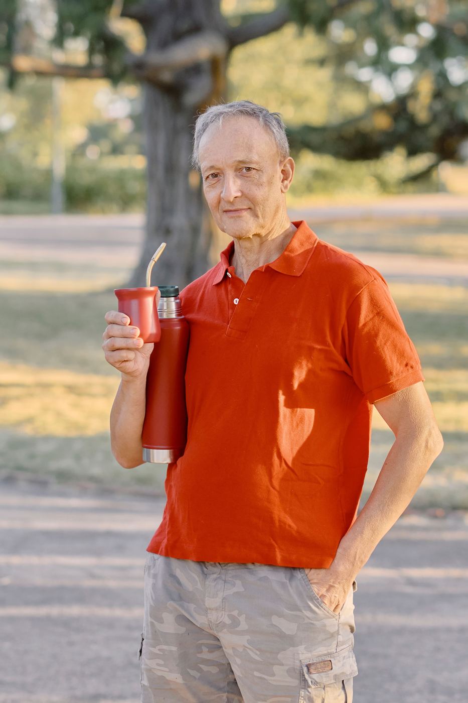 A man in a Buenos Aires park holding a traditional mate gourd with a metal bombilla straw