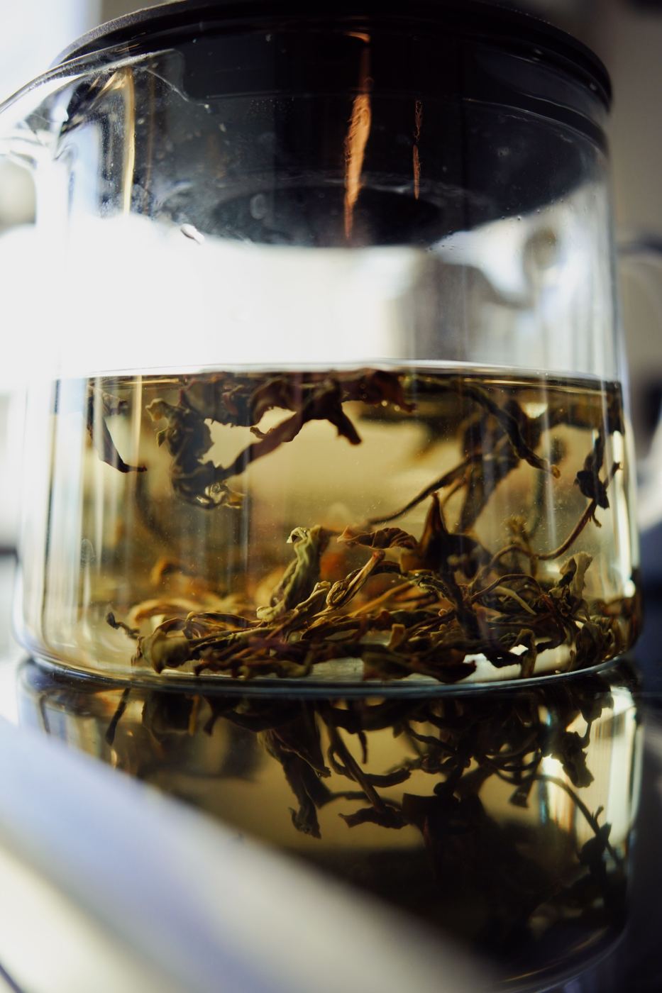 Loose leaf tea steeping in a glass teapot