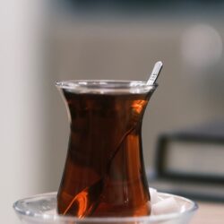 Dark, strongly brewed tea in a Turkish-style glass with a sugar cube