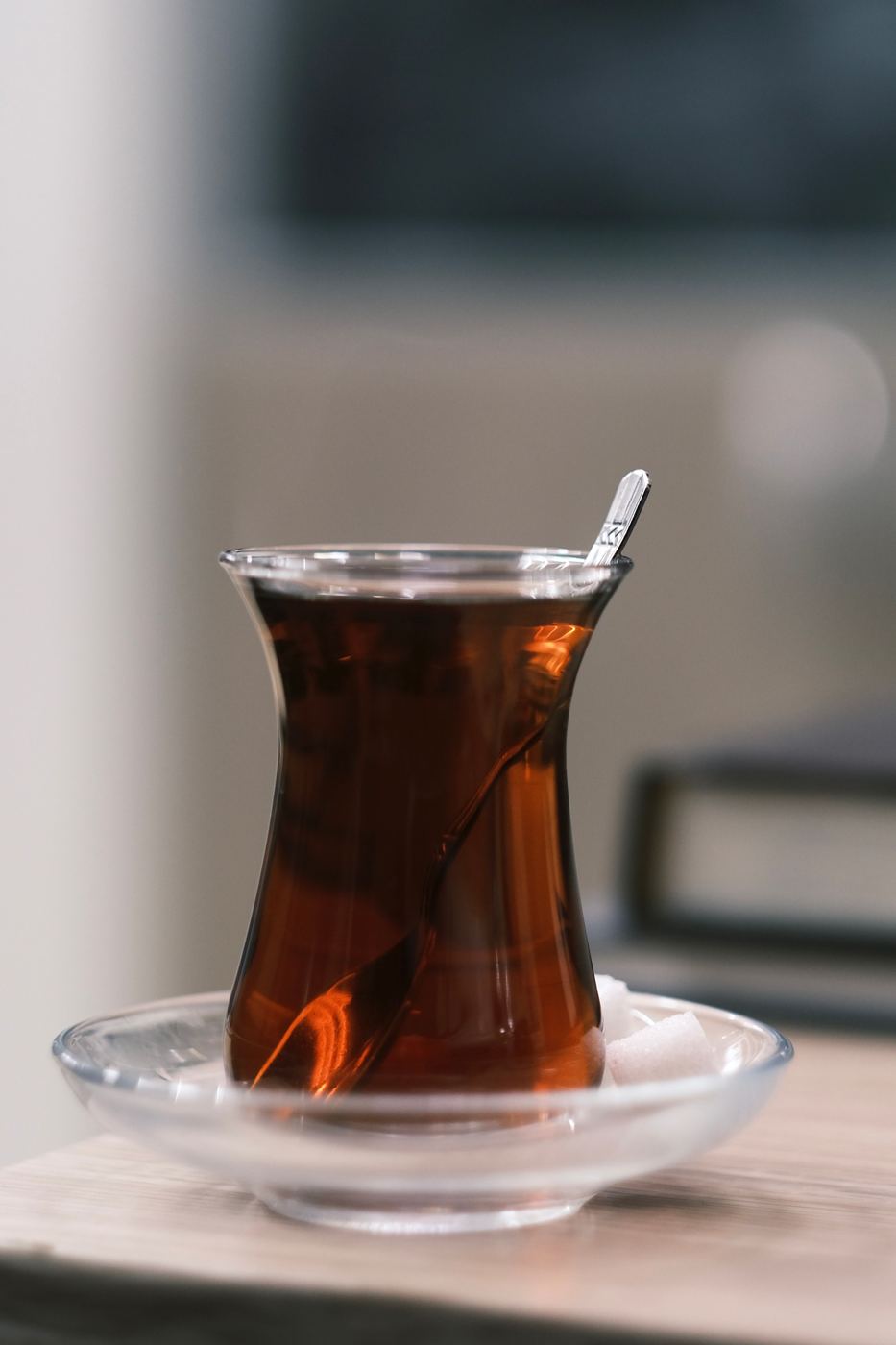 Dark, strongly brewed tea in a Turkish-style glass with a sugar cube