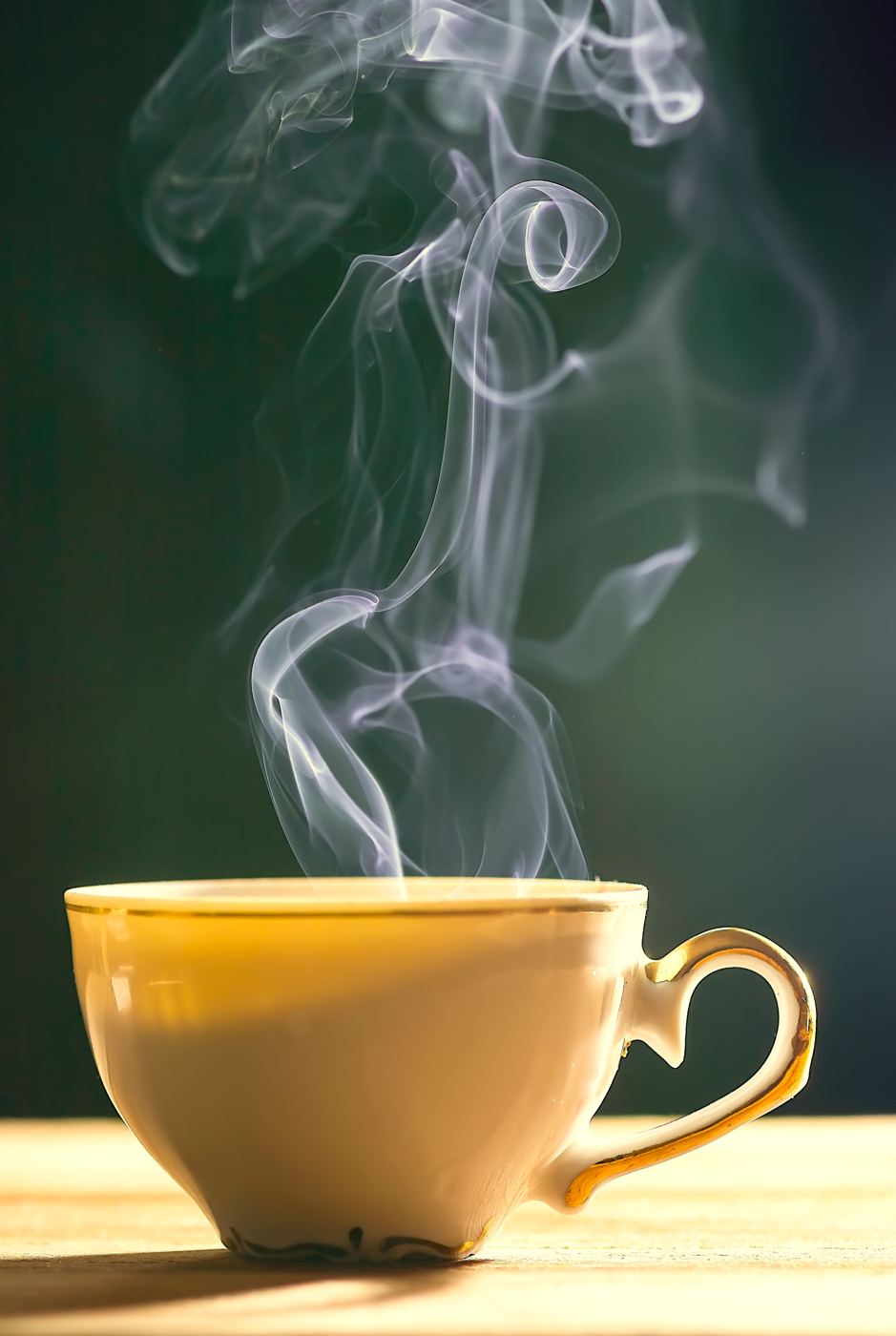 Steaming pale golden tea in a yellow ceramic cup against a dark background