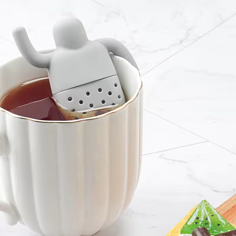 Tea infuser shaped like a person lounging in a cup of Moody Teas loose leaf tea.